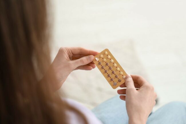 Une femme tient une plaquette de pilule contraceptive