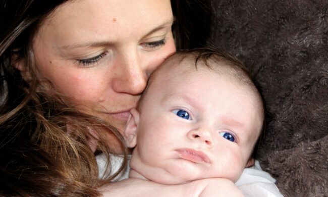 Une femme embrasse son tout jeune bébé