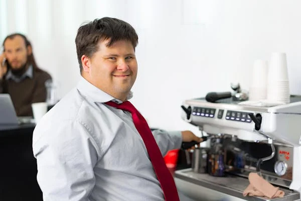 Homme trisomique souriant à la pause café dans une entreprise